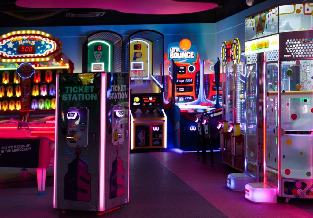 Bright arcade floor with games and ticket stations where an arcade photo booth fits
