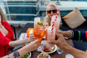 Friends raising glasses at a rooftop bar, the payoff of good bar promotion ideas