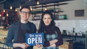 Cafe owners holding an open sign in their shop
