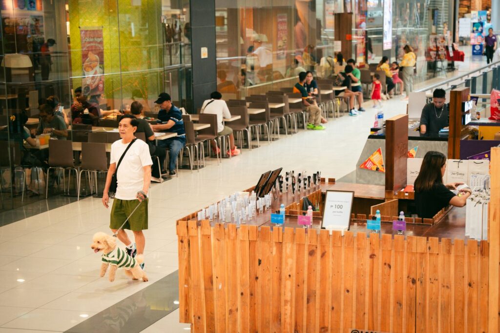 Shoppers in a bright indoor mall where a mall photo booth draws families