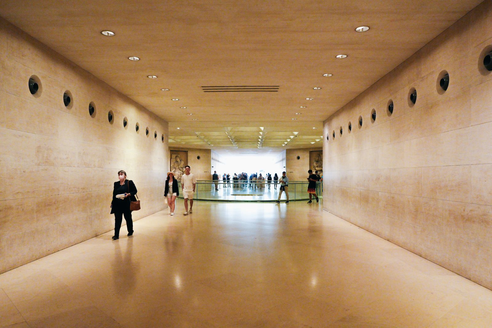 Visitors walking a bright museum corridor where a museum photo booth could sit