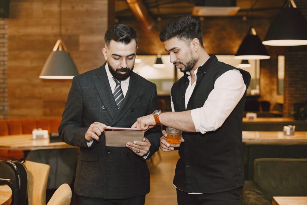 Two business owners reviewing numbers on a tablet in a cafe