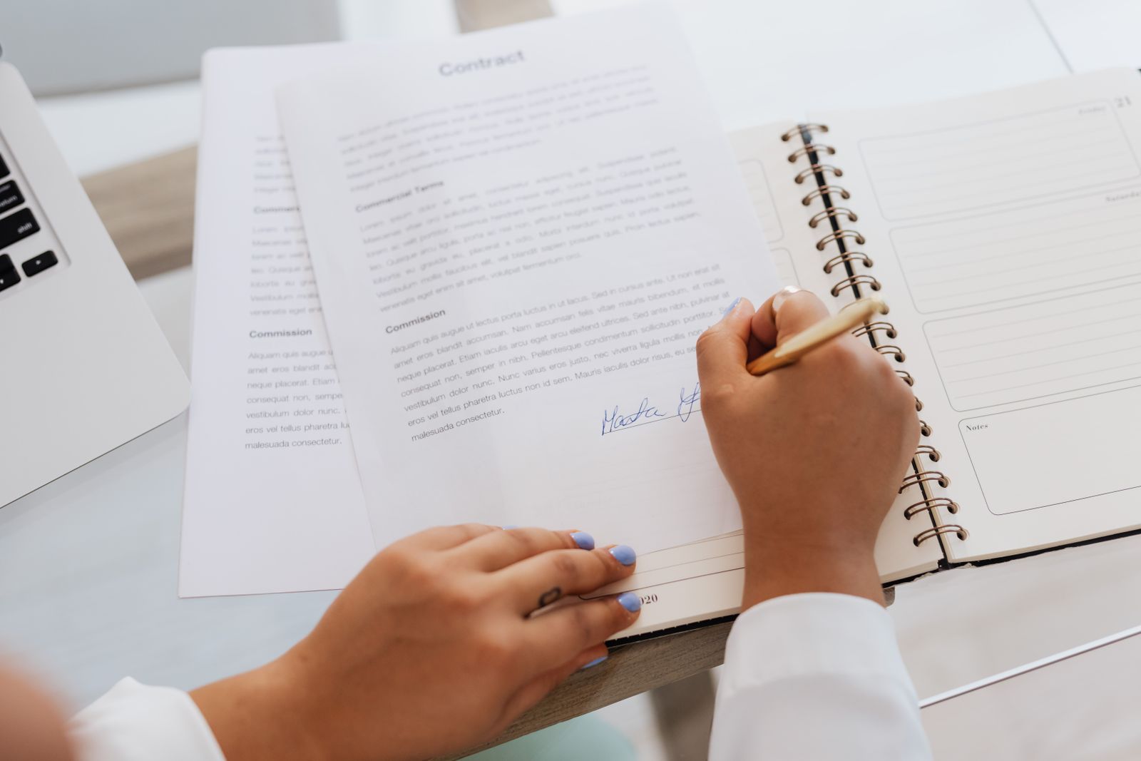 Hands signing a contract on a desk