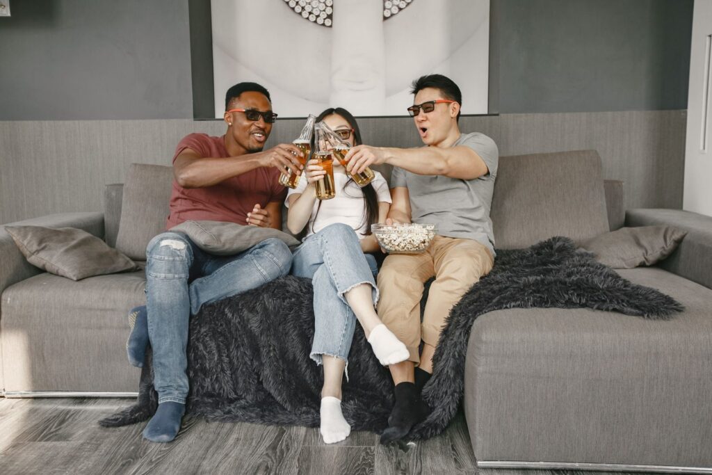 Three friends relaxing on a sofa with drinks