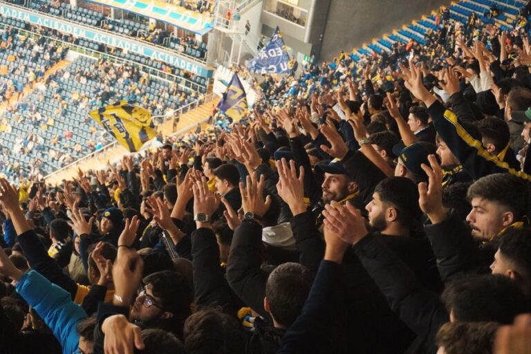 Fans cheering with raised hands in a stadium